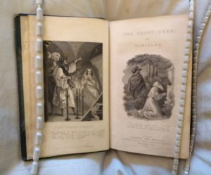 Book open to its frontispiece and title page, with spooky illustrations on both